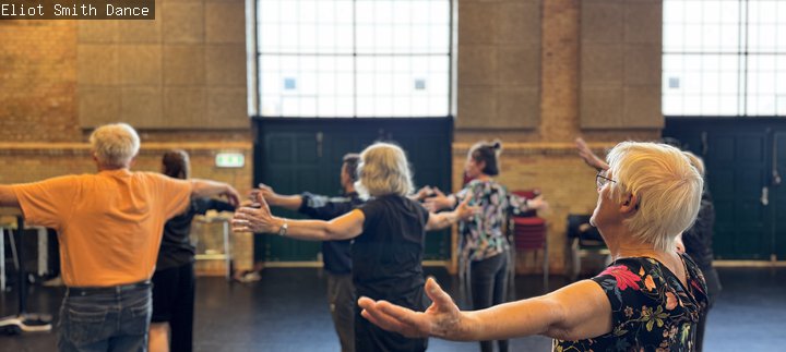 People standing inside a room with their arms wide out in dance 