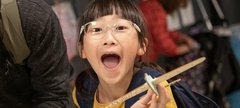 girl in Play Invent gallery holds her creation and laughs at camera