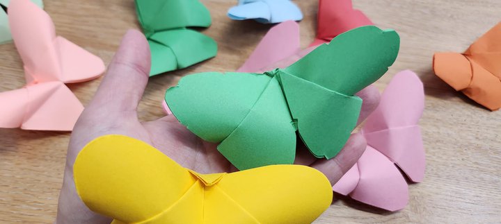 A selection of paper butterflys in coloured paper lying on a table 