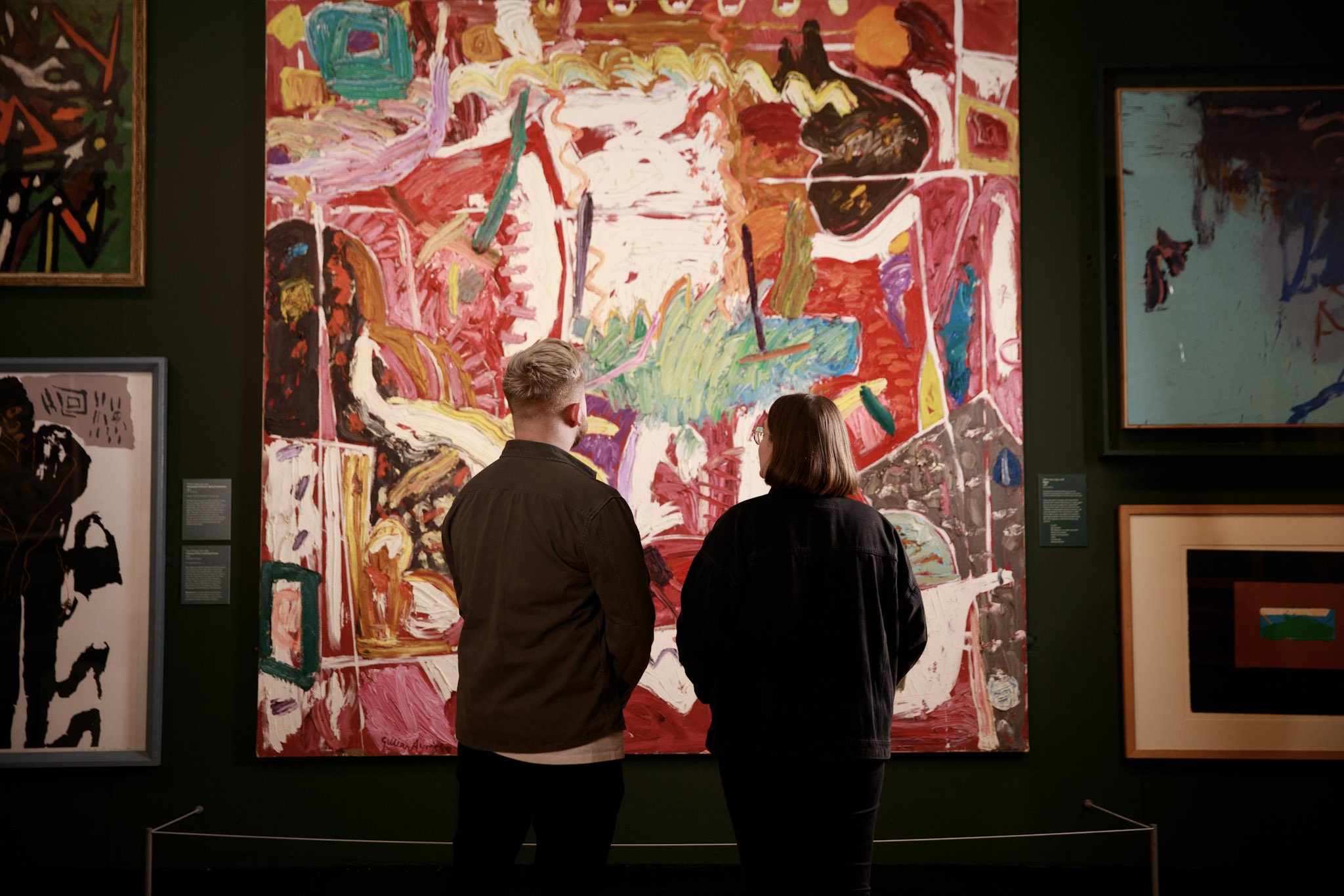 A man and woman looking at an abstract painting in an art gallery.