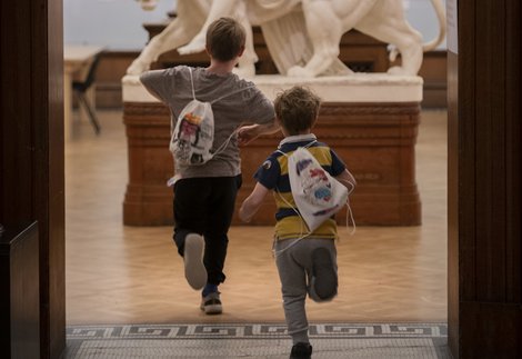 Two children running in an art gallery