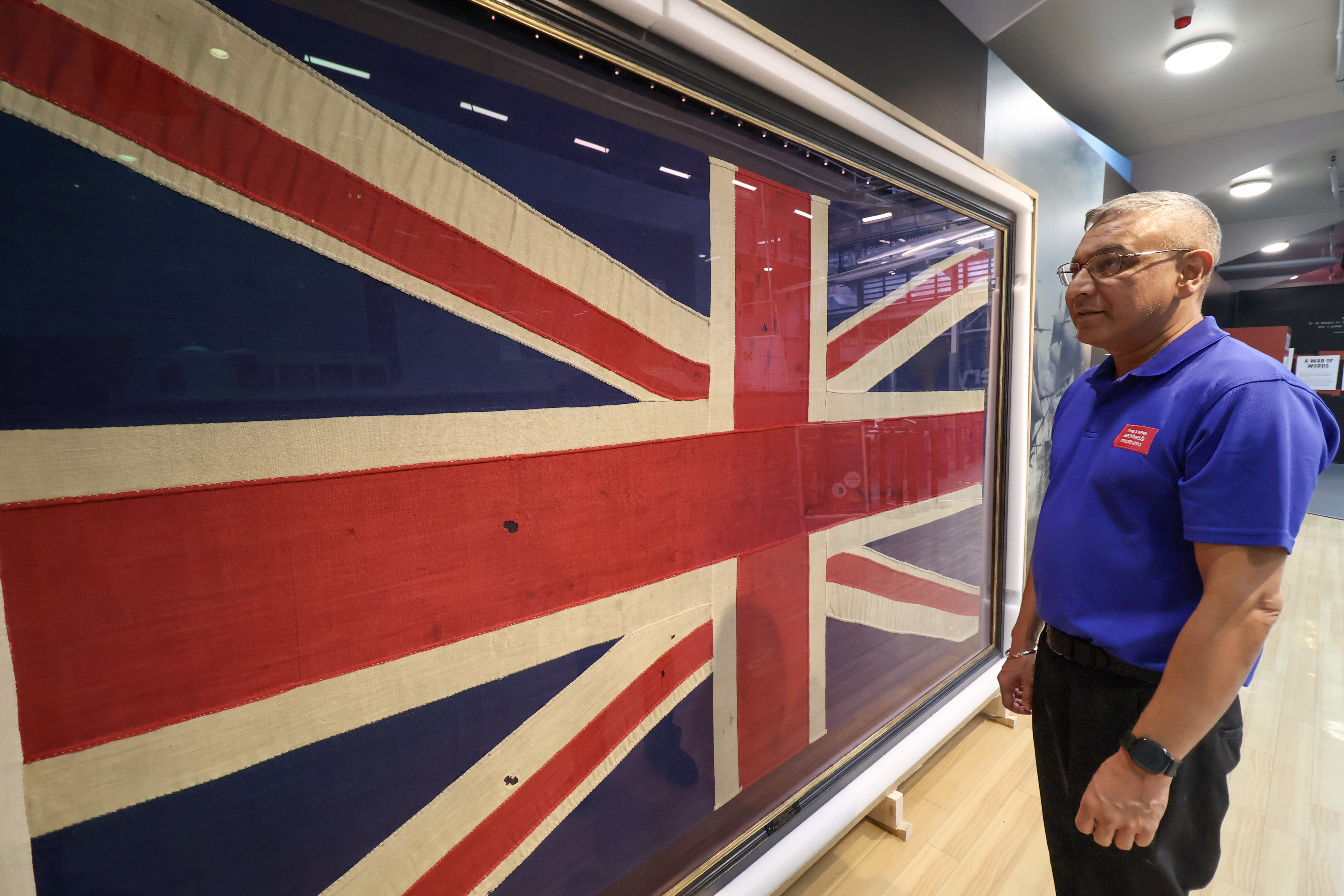 man in blue shirt looks at large Union flag in case