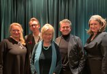 Five people standing in front of a blue velvet curtain