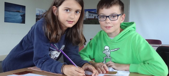 A boy and a girl embossing designs onto a copper sheet