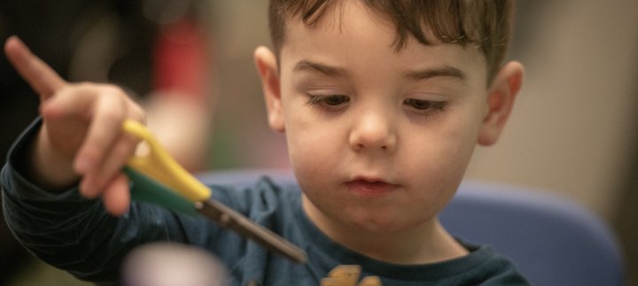A young child is cutting some paper.