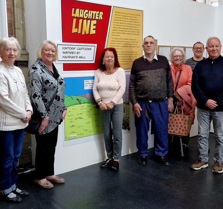 Group of people standing next to an exhibition of drawings and cartoons
