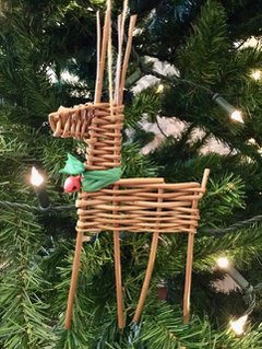 Wicker reindeer with a red nose against a background of green foliage