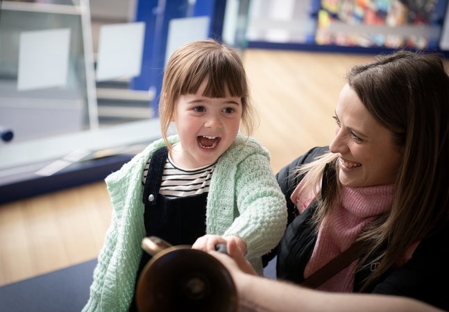 little girl laughs with mum in museum