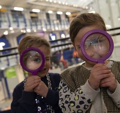Two girls peer through magnifying glasses