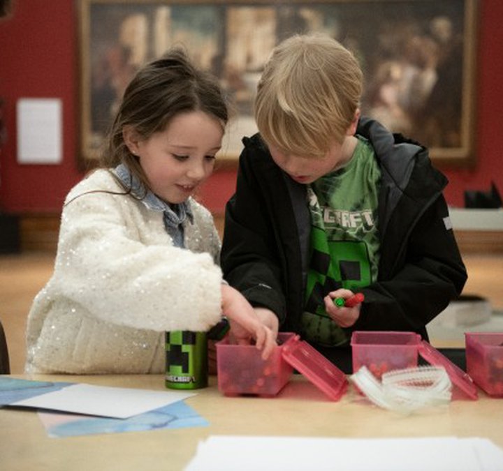 Two children looking in a box of pens together.
