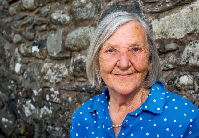 A photograph of a woman wearing a blue and white polka dot shirt.
