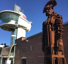 Iron sculpture of Roman soldier with viewing tower in the background