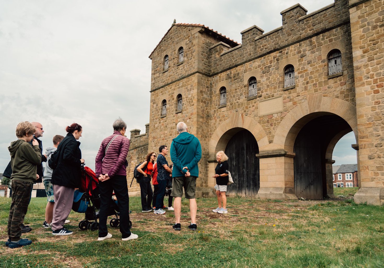 A group standing outside a large stone gate, listening to a tour guide