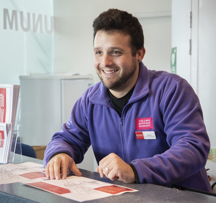 Man in purple fleece behind reception desk