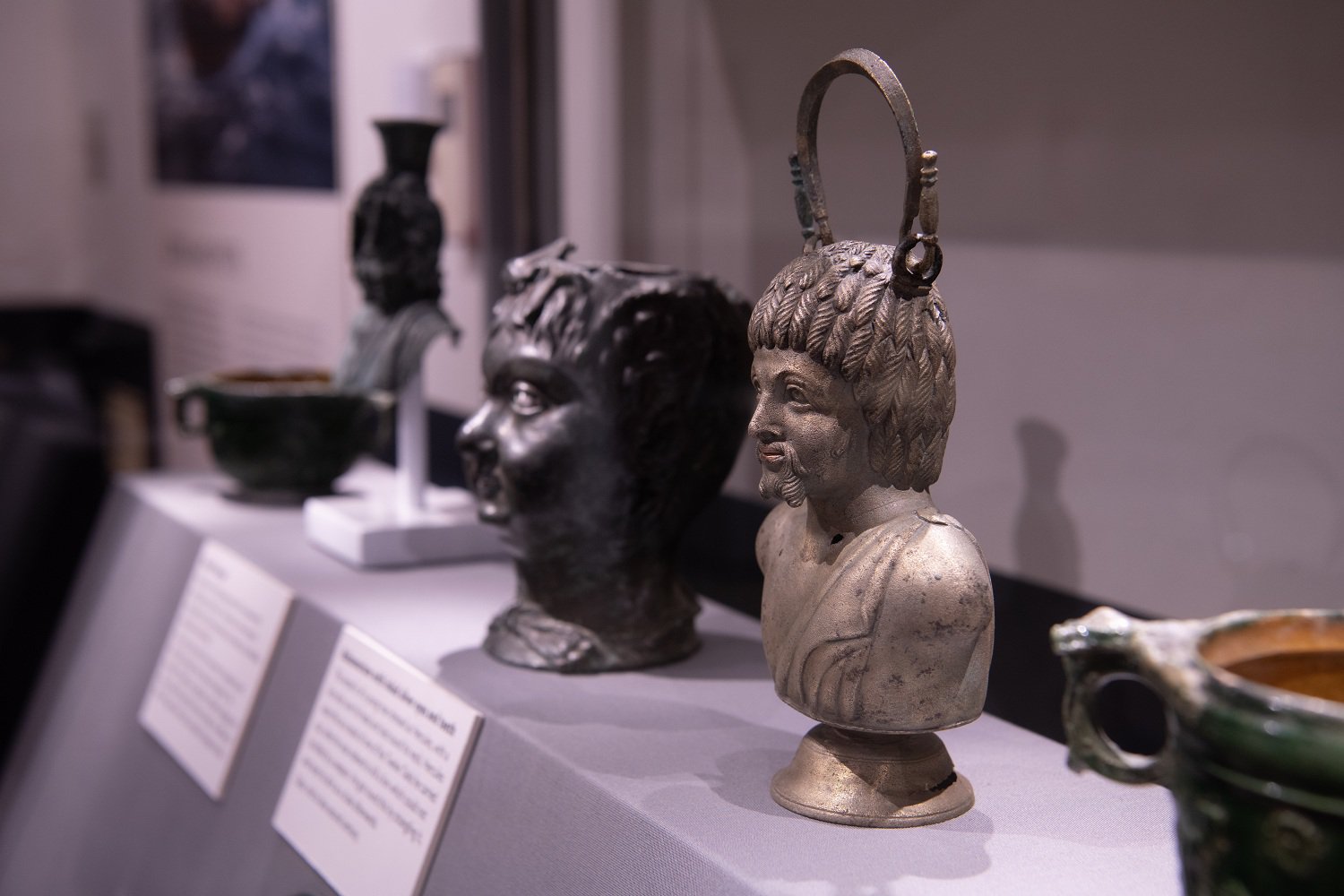 Metal Roman figurine busts in a museum display case.