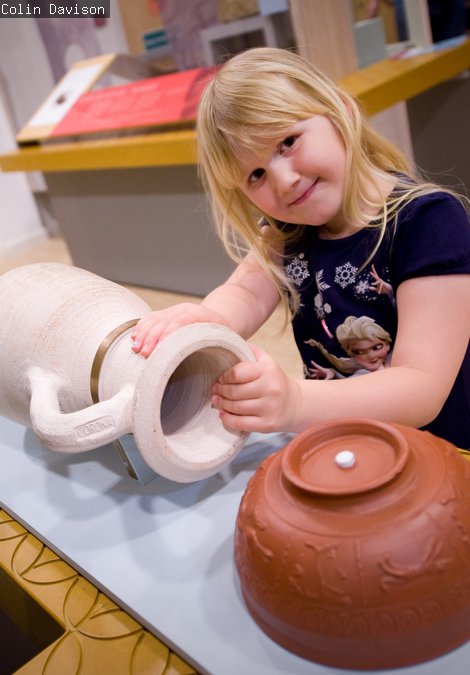 Child with three roman pottery handling objects