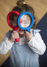 Small girl peers through toy magnifying glasses