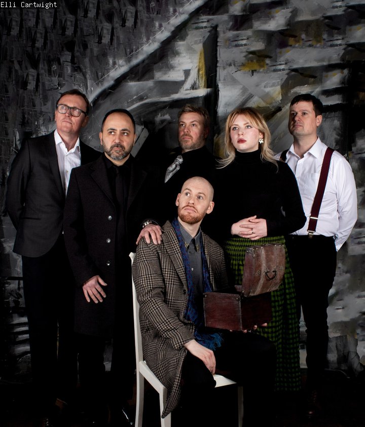 One person sitting down with five people stood up behind him.