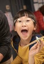 girl in Play Invent gallery holds her creation and laughs at camera