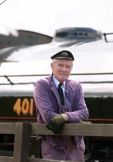 Man with cap in front of black steam locomotive
