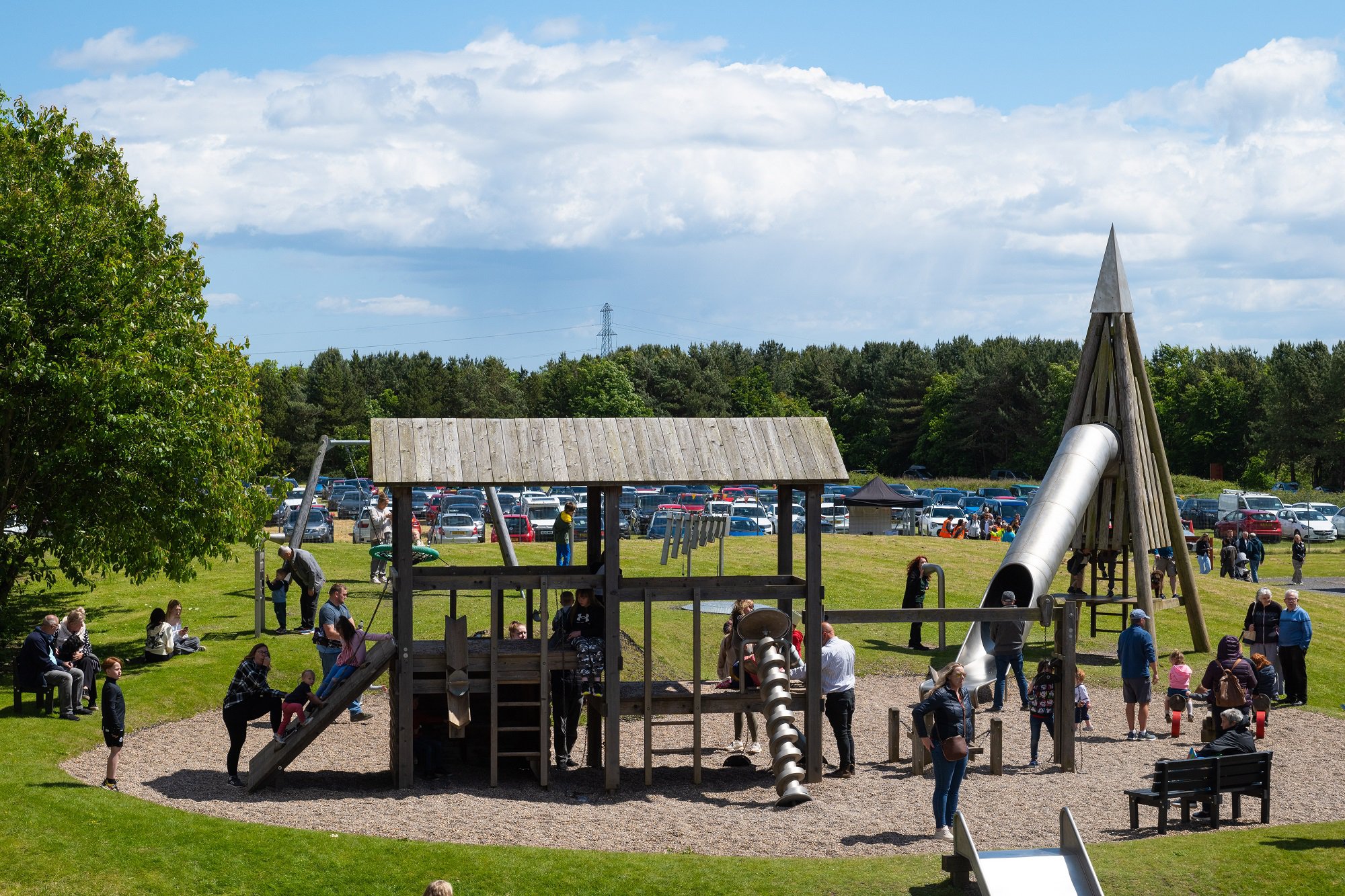 View of families playing together on a wooden adventure play area.