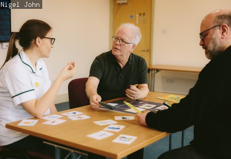 Three people sit at a table playing a game