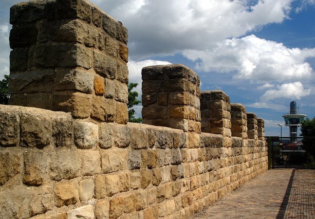 Modern reconstruction of Hadrian's Wall with Segedunum Roman Fort viewing tower in background
