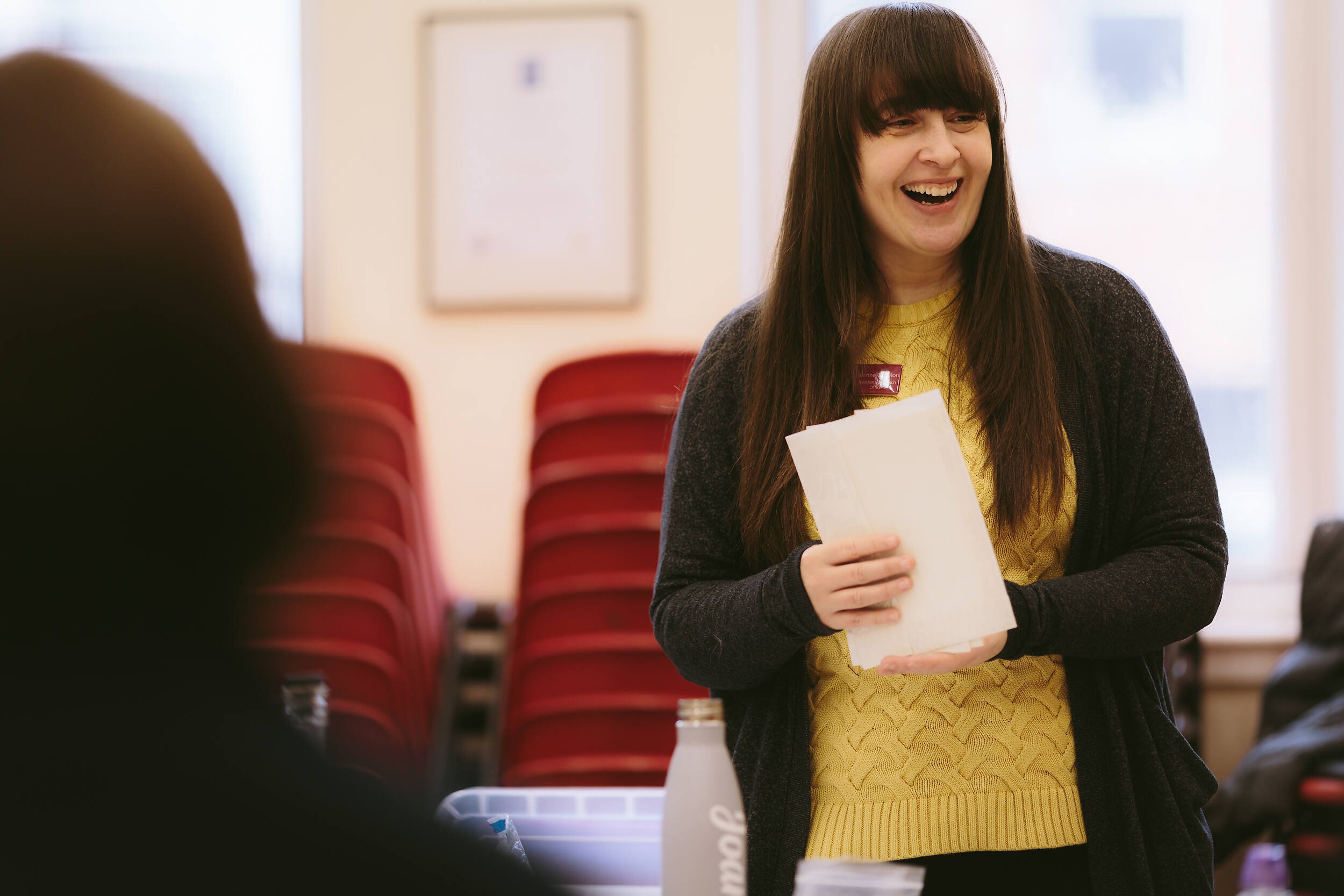 A woman smiling enthusiastically as she runs a museum outreach session.