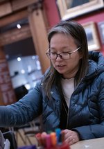 A person sitting at a table and taking part in a creative activity.