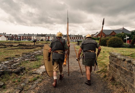 Two people from behind dressed as Romans walk a path 