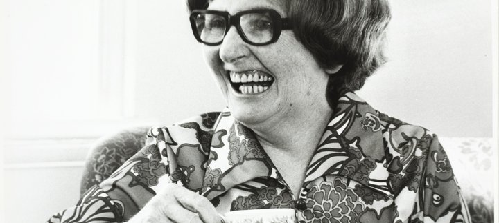 Dame Catherine Cookson laughs holding a cup of tea
