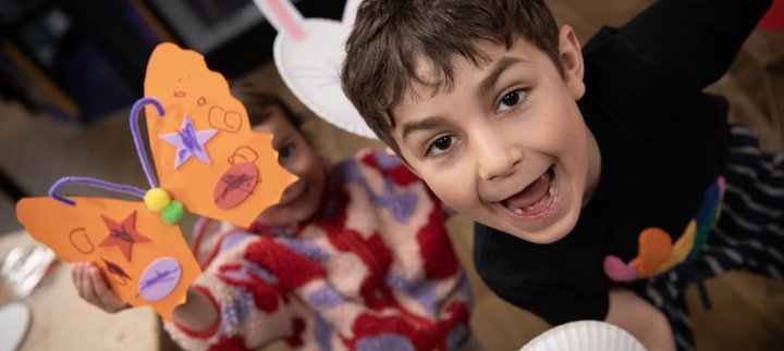 two children hold up their creations and smile