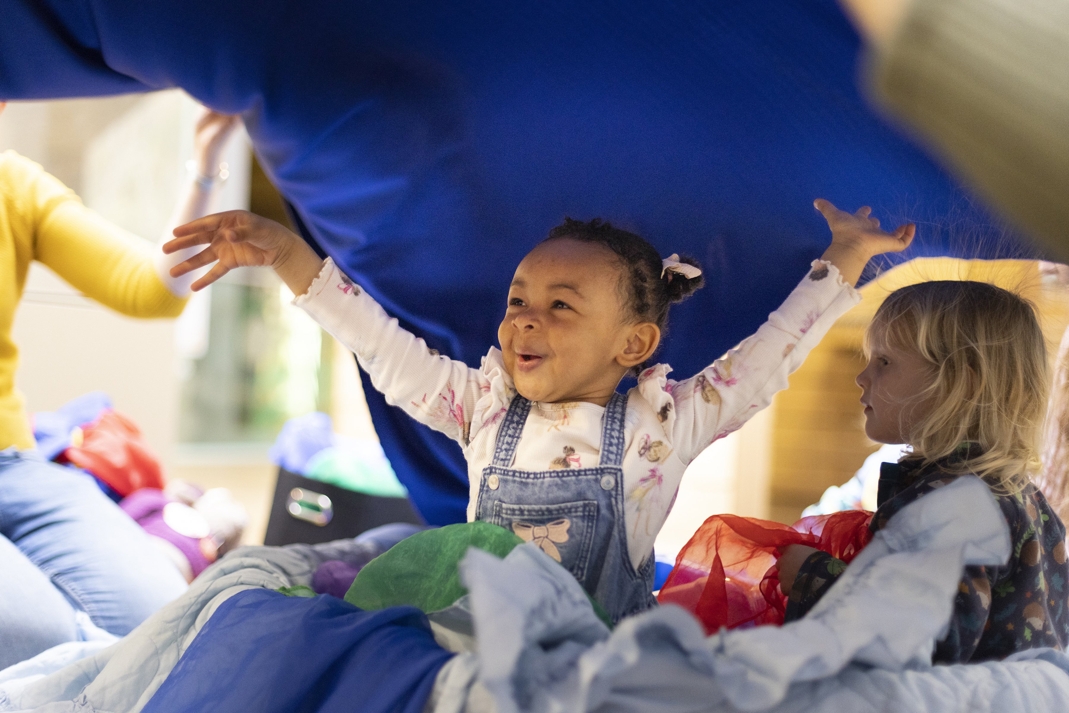 A little girl is smiling with her arms in the air.