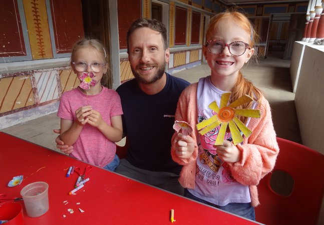 Two young girls with their dad holding the flowers they've made from egg boxes
