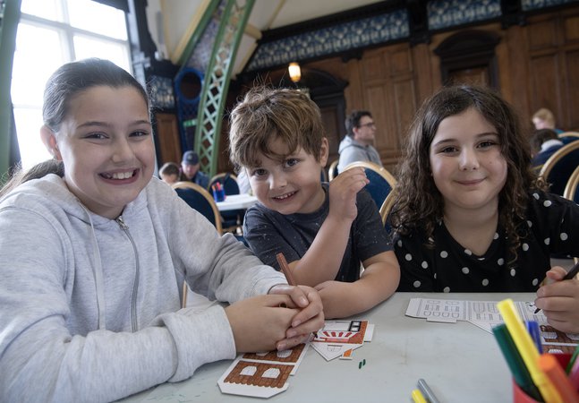 two girls and a boy smile while doing crafts 