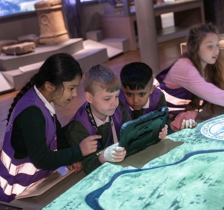 Children taking holding iPads next to a Hadrian's Wall model. 