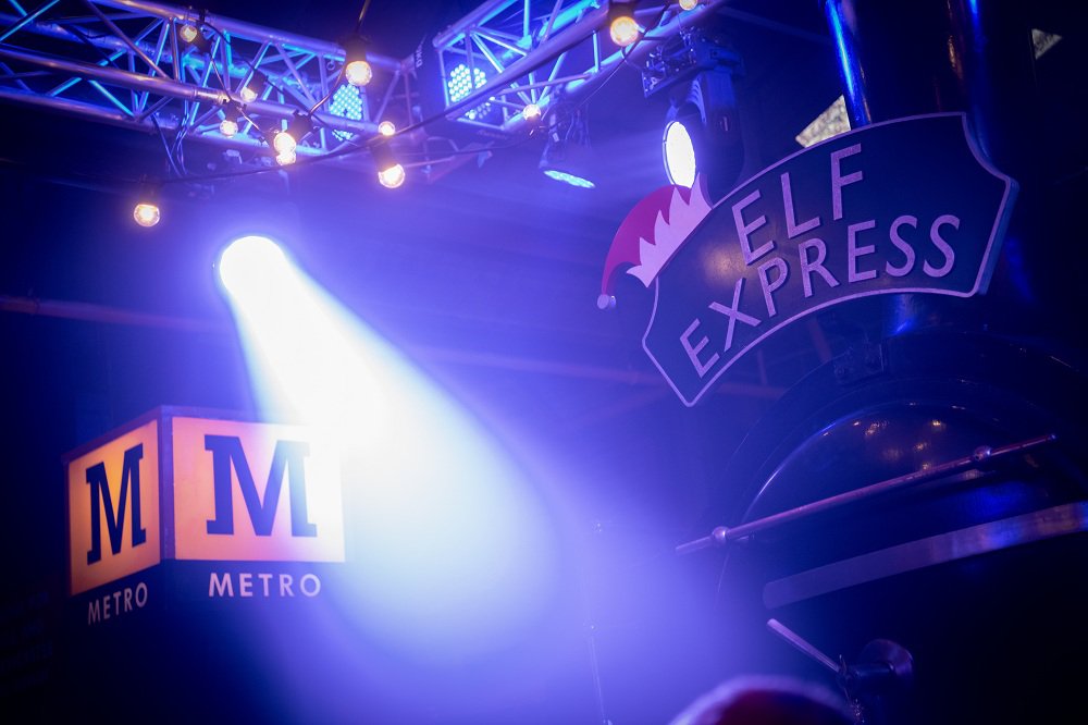 Stage lighting in a railway museum. We see a train with 'Elf Express' on the headboard. Stage lighting in a railway museum. We see a train with 'Elf Express' on the headboard.