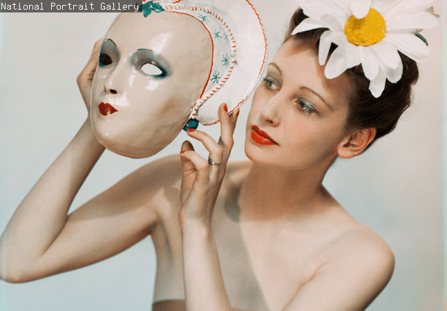 A woman holding a mask on a pale background