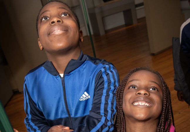 boy and gilr smile up towards camera in gallery 