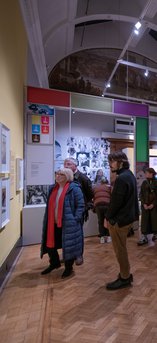 A younger man and older woman looking at a photograph on the wall.