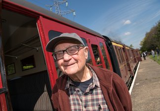 Man wearing cap standing next to railway carriage