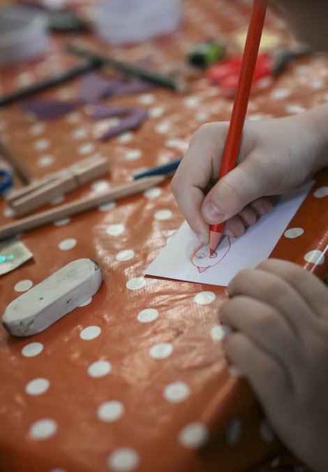 child with pencil in hand at a craft table