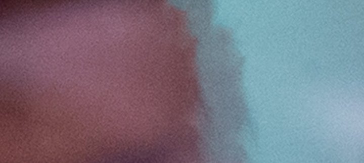 A toddler is standing next to light box cube which is placed on the ground, the toddler is holding a wooden toy.