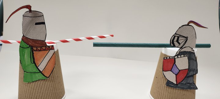 Two knights crafted from paper coffee cups and with straws for swords stand opposite each other ready to joust
