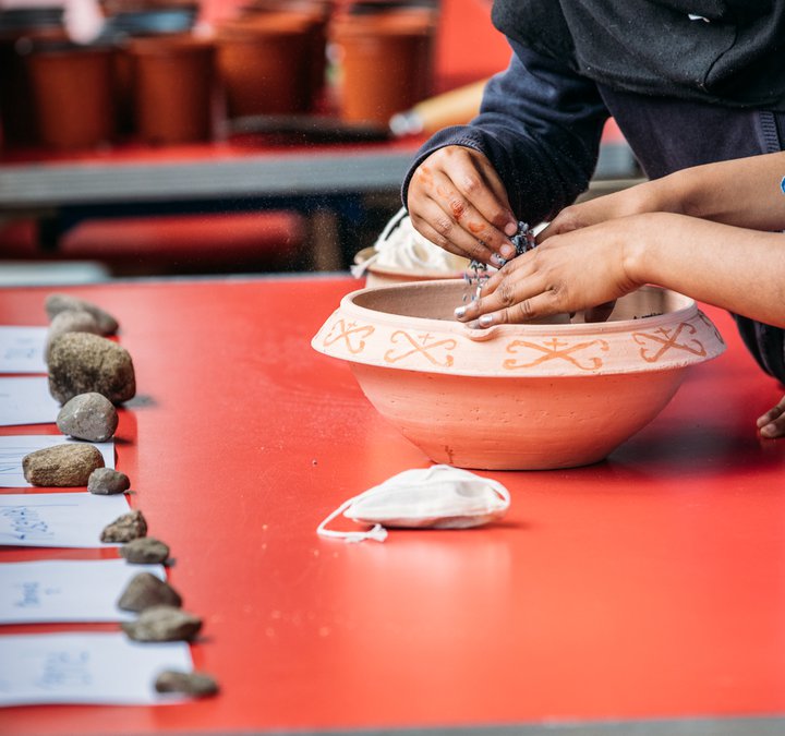 Children's hands planting herbs in a container on a table