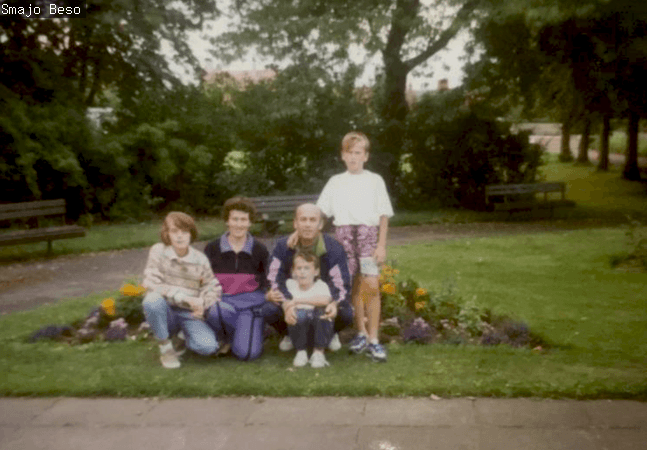 A grainy 1990s photo of a family smiling 