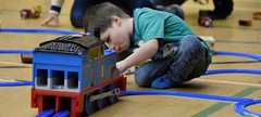A small boy plays with a large train set 