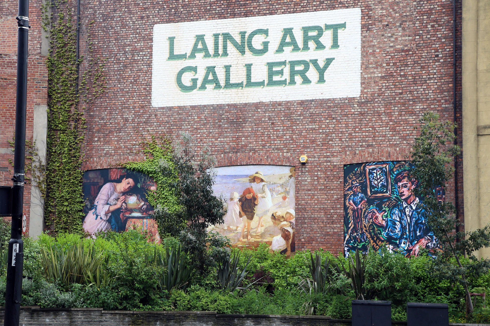 Exterior of the Laing Art Gallery. Brick building with large-scale recreations of paintings that can be seen inside.