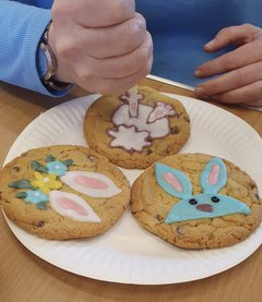 A photograph of someone decorating cookies with a spring theme, including bunnies and flowers.