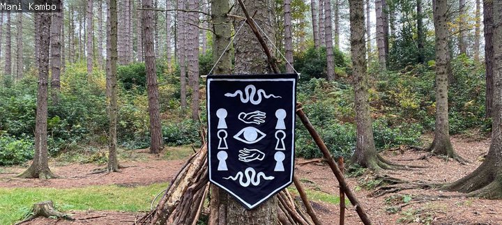 A black and white embroidery hanging from a tree. 